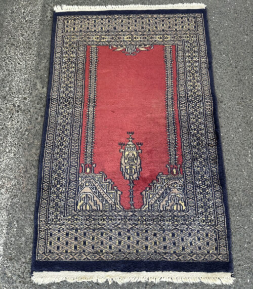 Handgeknüpfter Orientteppich mit rotem Feld und dunkelblauer Bordüre 102 x 62 cm