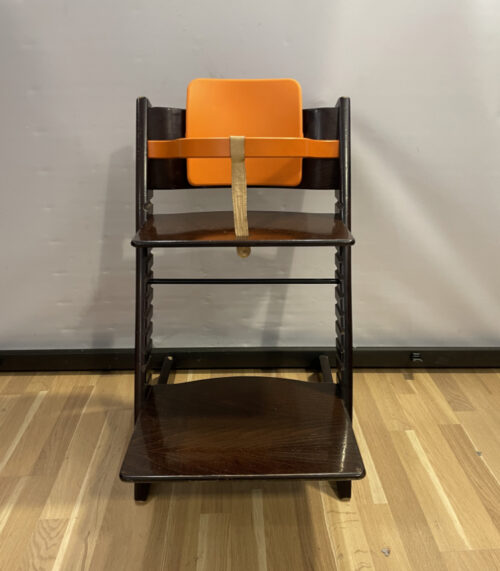 Kinderhochstuhl Stokke Tripp Trapp aus dunklem Holz mit oranger Babyeinlage