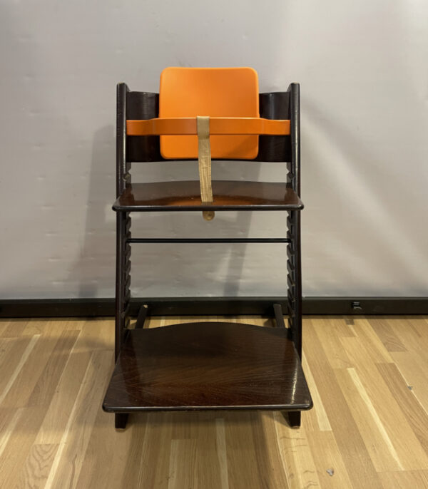 Kinderhochstuhl Stokke Tripp Trapp aus dunklem Holz mit oranger Babyeinlage